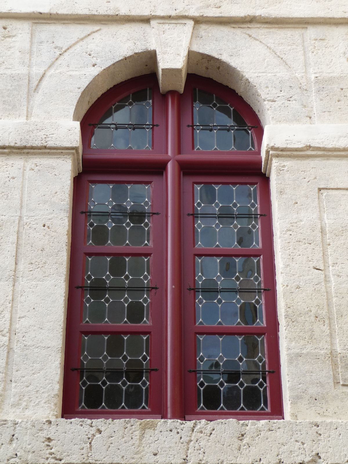 Fenêtre bois à croisée de meneaux avec vitraux, dans une façade en pierre